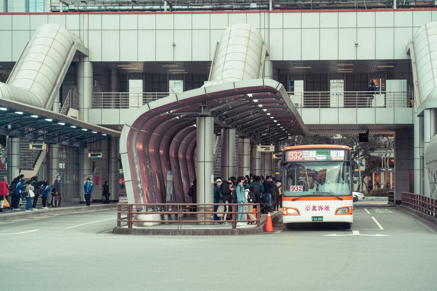 Public transport bus picking up commuters at a modern urban terminal with architectural features.