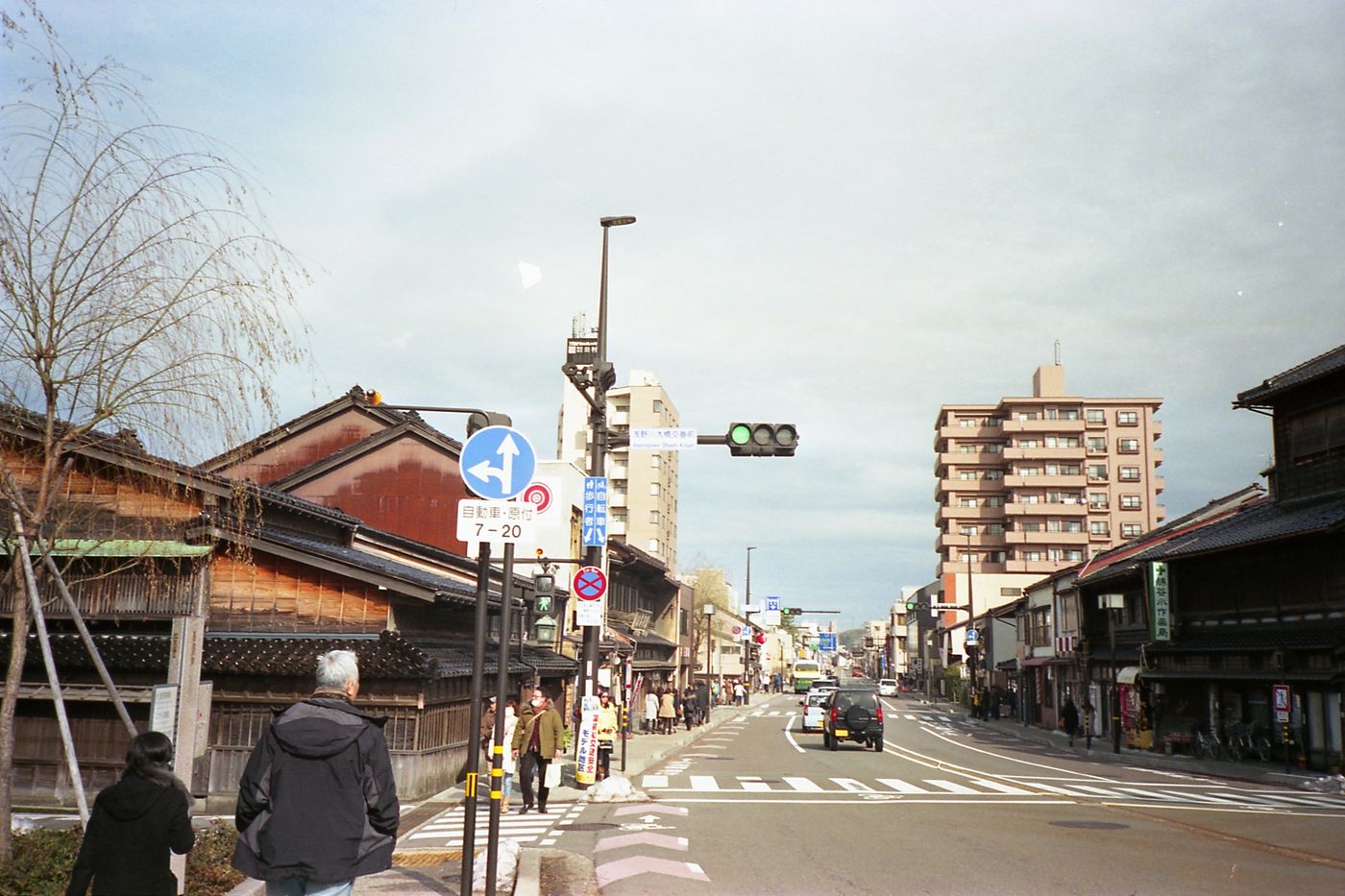 Street view of Kanazawa showcasing traditional and modern architecture with pedestrians and traffic.