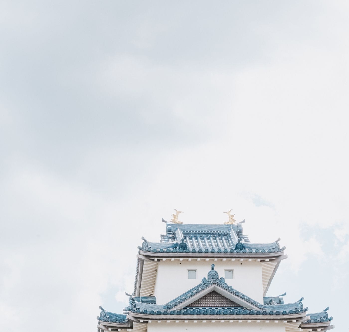 Elegant view of a traditional Japanese castle rooftop against a bright sky.