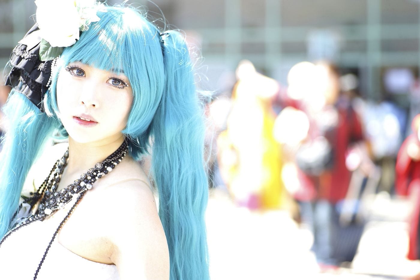 Vibrant cosplay portrait of a woman with blue hair and intricate costume in bright outdoor setting.