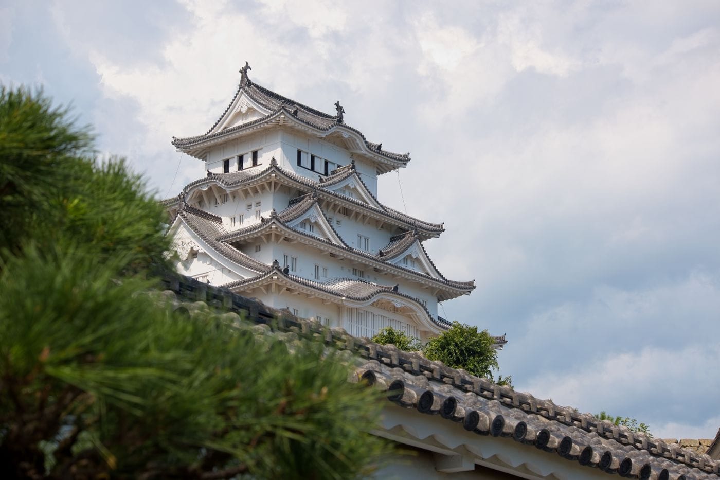 Himeji Castle against a cloudy sky, showcasing traditional Japanese architecture.