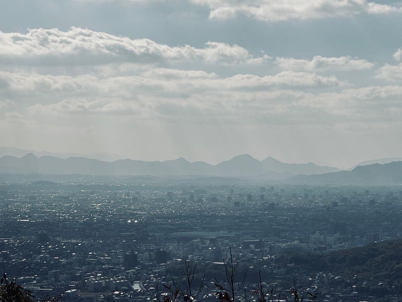Discover Takamatsu's skyline enveloped in mist with mountains in the backdrop.