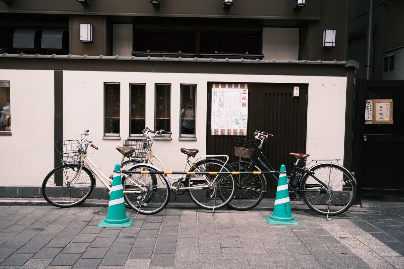 A row of bicycles parked in an urban Tokyo street, framed by modern architecture.
