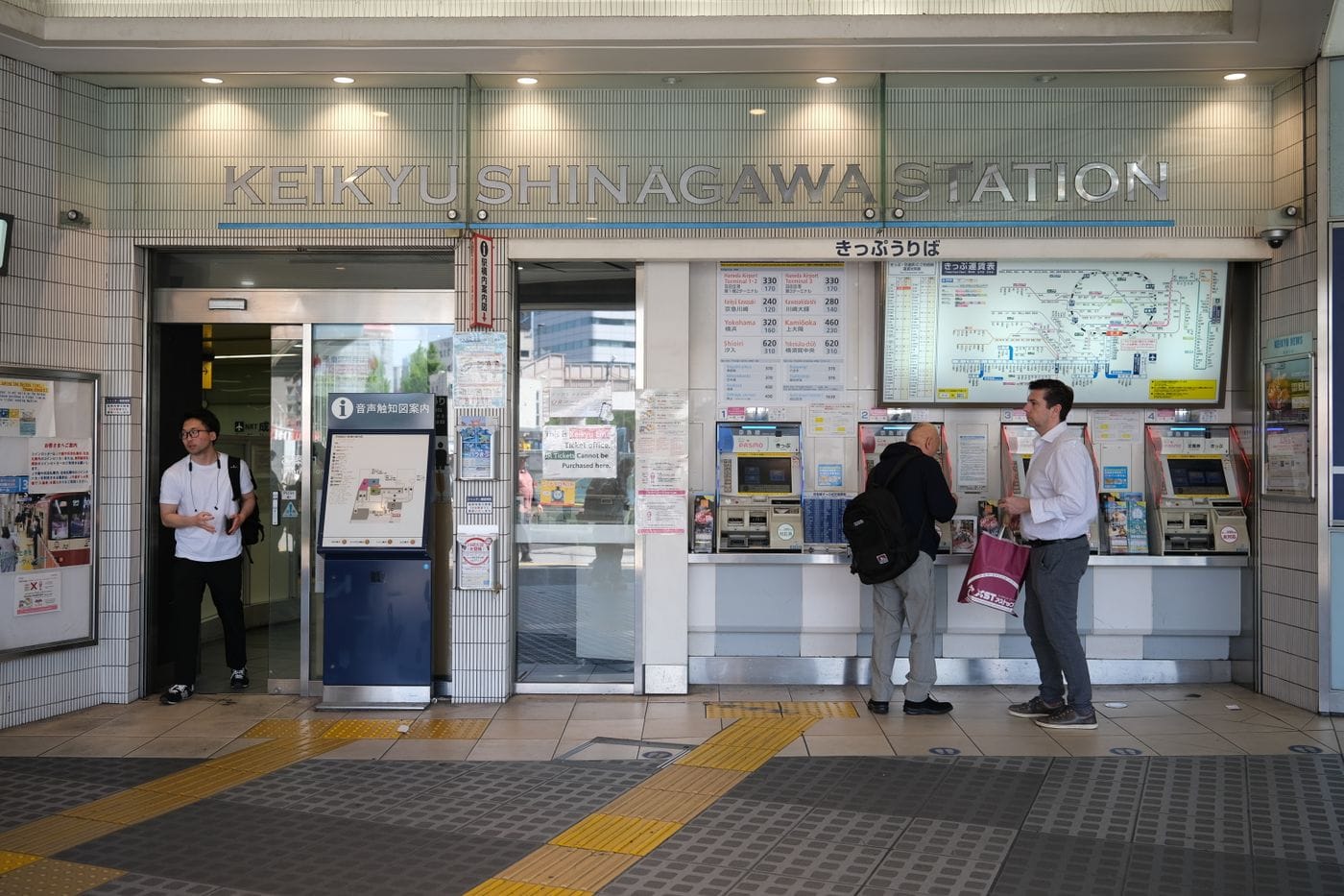 People at ticket machines at Keikyu Shinagawa Station, Tokyo, Japan, bustling rail station scene.
