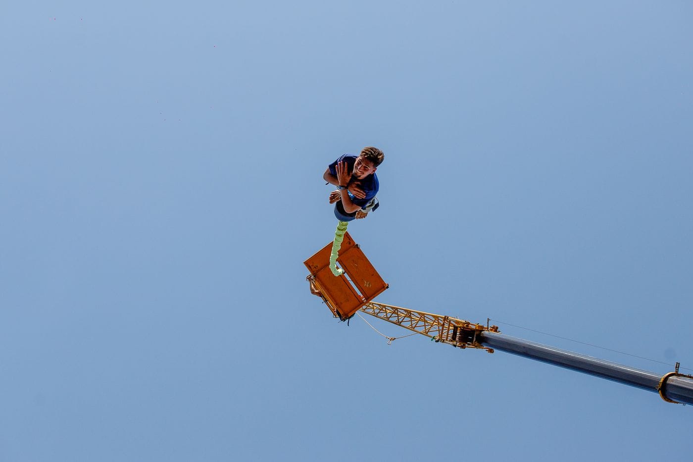 Daring bungee jump from crane, capturing the thrill and adrenaline in the sky.