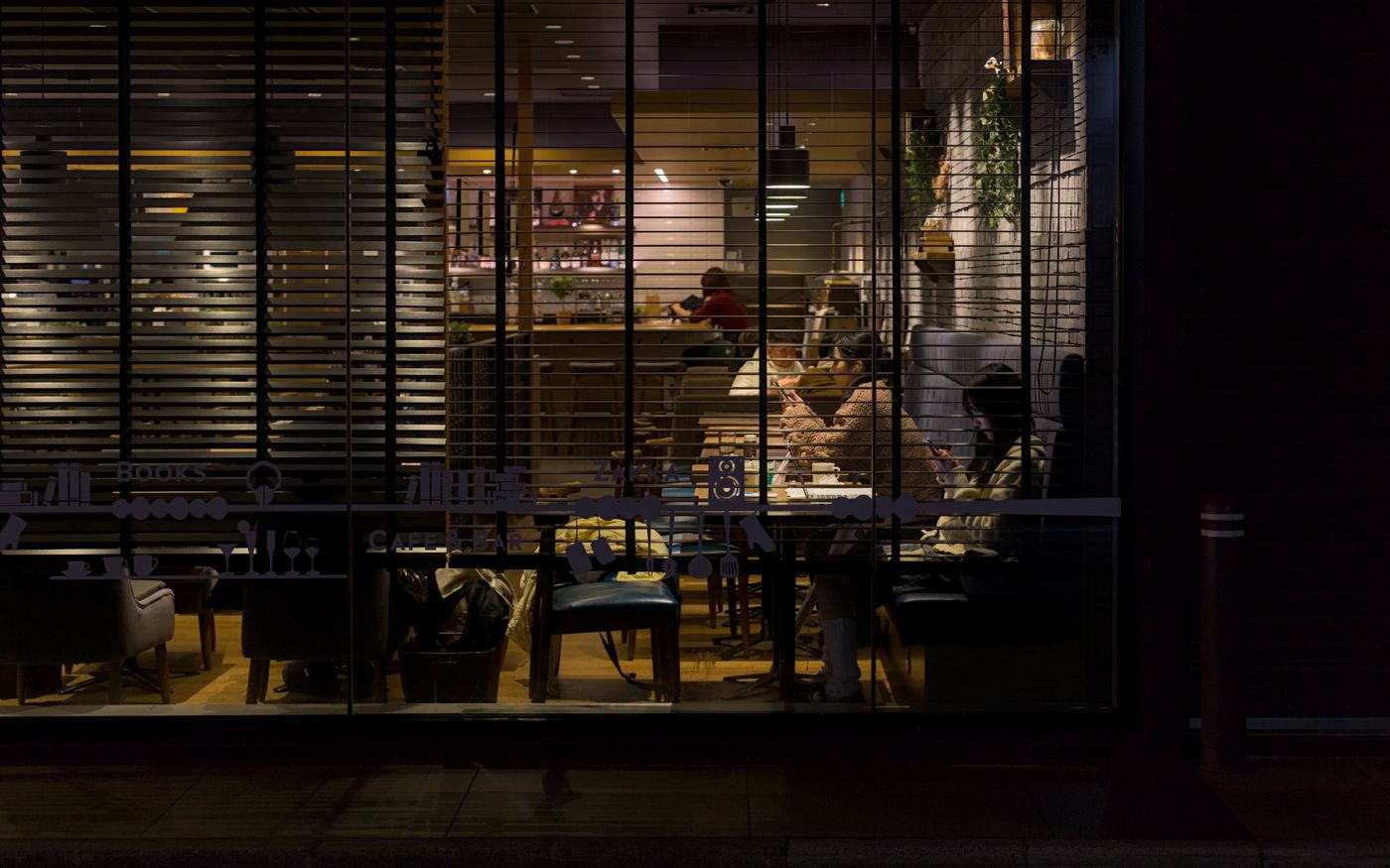 Nighttime view of a cozy Kyoto café illuminated with soft lighting, capturing a warm and inviting urban atmosphere.