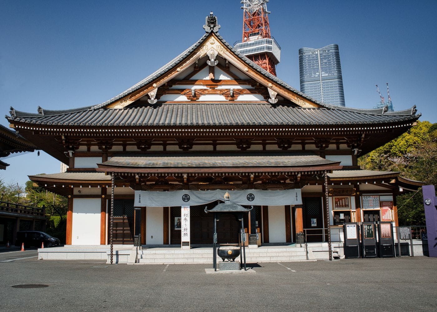 Front view of Zojoji Temple in Tokyo, Japan with Tokyo Tower visible behind, under clear skies.