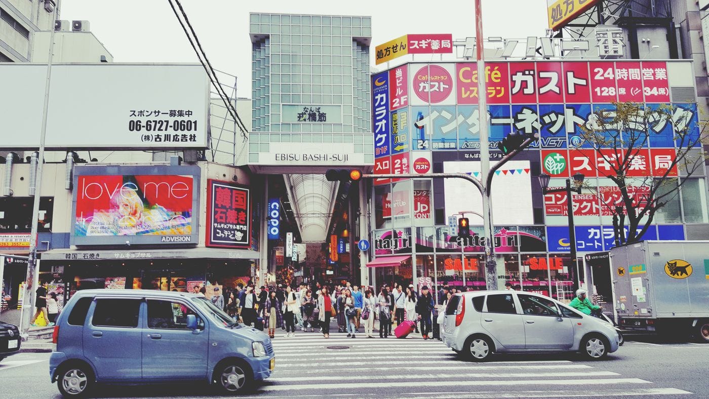 Vivid street view of Ebisu Bashi-Suji, Osaka with vibrant signs and pedestrians crossing.