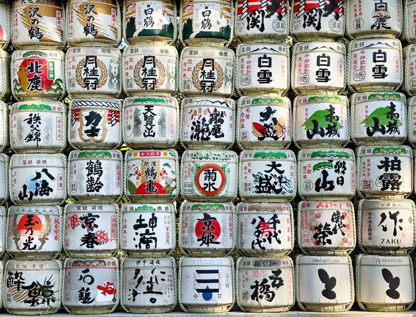A vibrant display of traditional sake barrels with intricate Japanese calligraphy.
