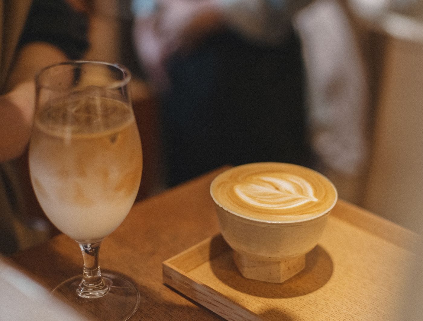 Artistic coffee latte and iced drink on wooden tray in Tokyo café, capturing the essence of Japanese coffee culture.