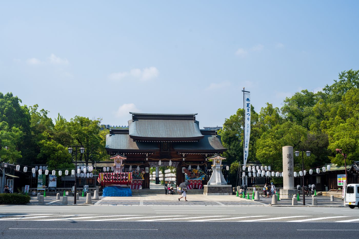 Traditional Japanese shrine gate with lanterns in Ise. Clear sunny day outdoors.