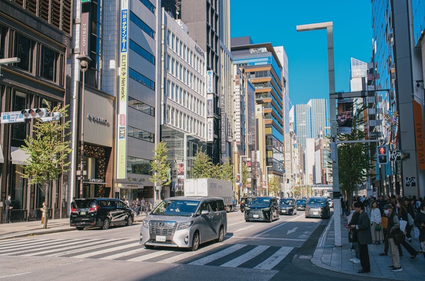 Daytime view of a busy Tokyo street with modern skyscrapers and pedestrians.