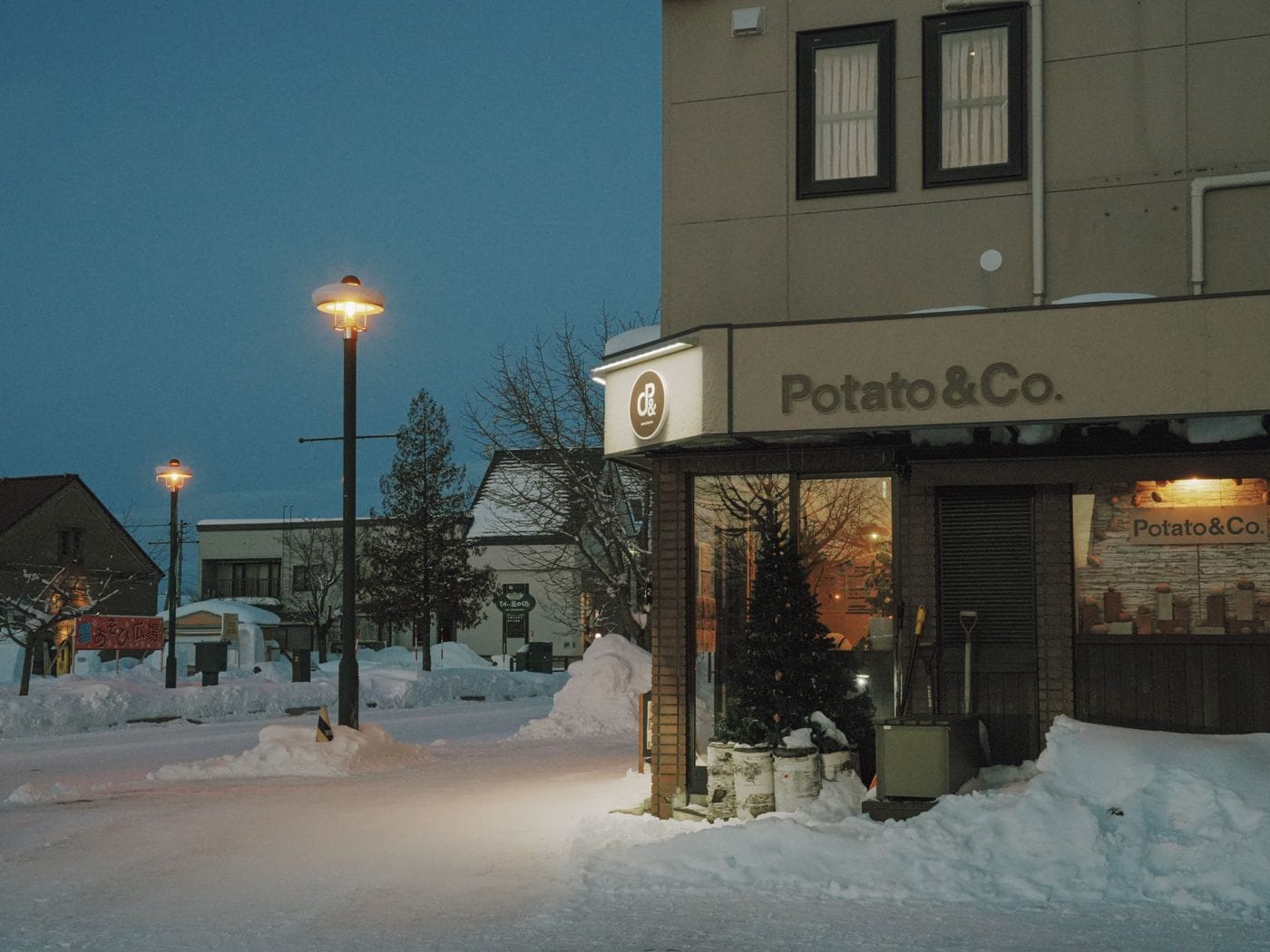 Snowy street in Hokkaido, Japan with cozy shops and streetlights at night.