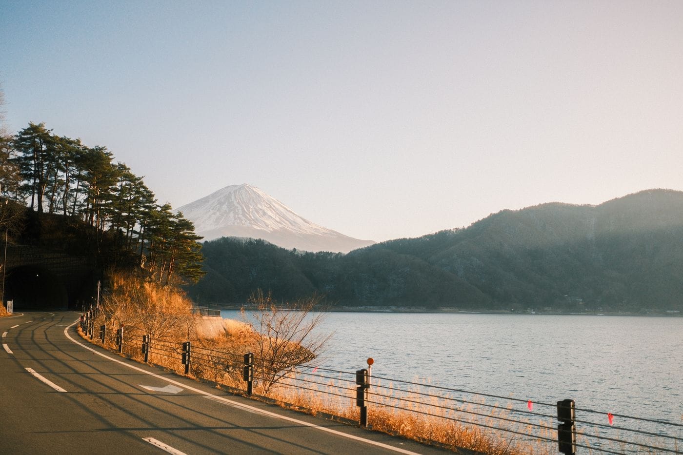 Serene lakeside road with Mount Fuji backdrop in Fujikawaguchiko, Japan during sunset.