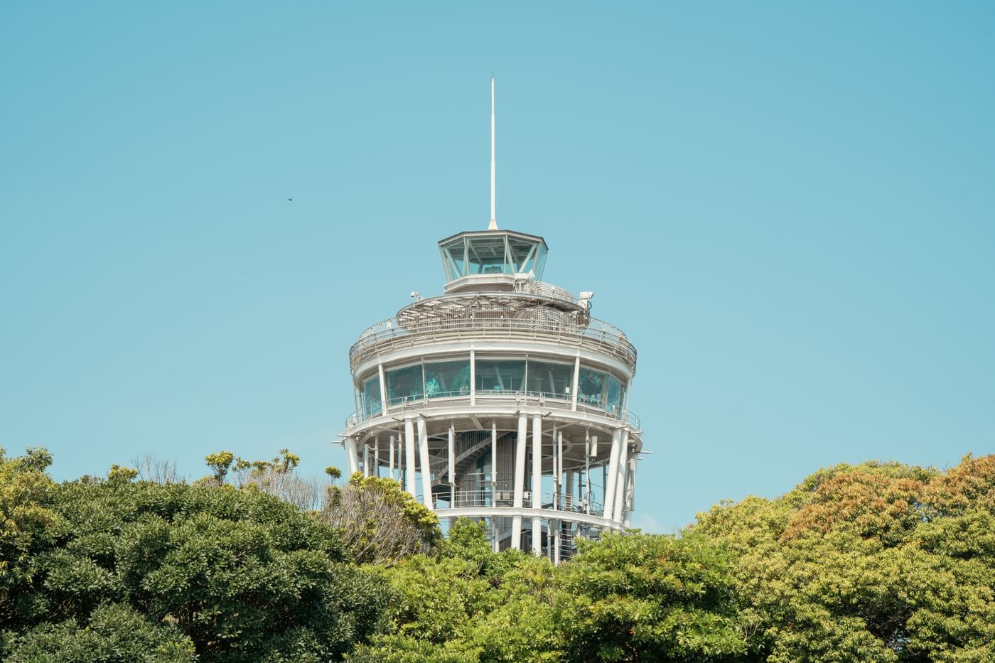 The iconic Enoshima Sea Candle tower surrounded by lush greenery in Fujisawa, Japan.