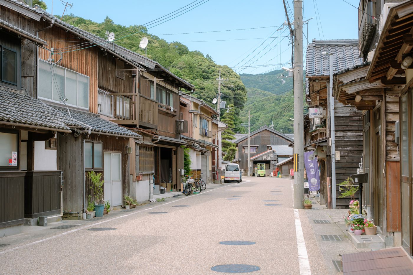 A serene view of a traditional Japanese street with wooden houses and lush greenery.