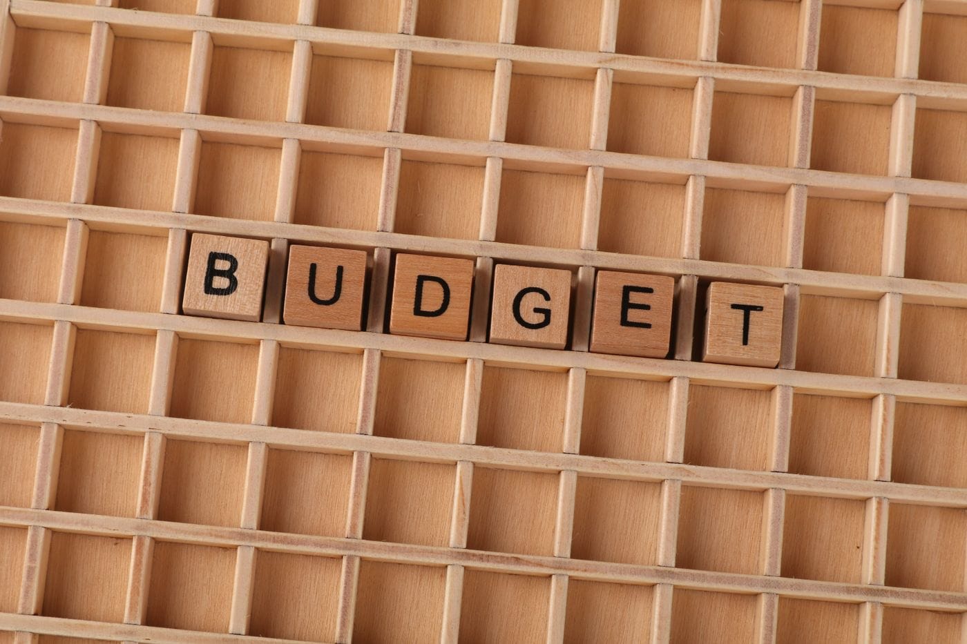 Wooden Scrabble tiles spelling 'budget' on a textured wooden grid, symbolizing financial planning.