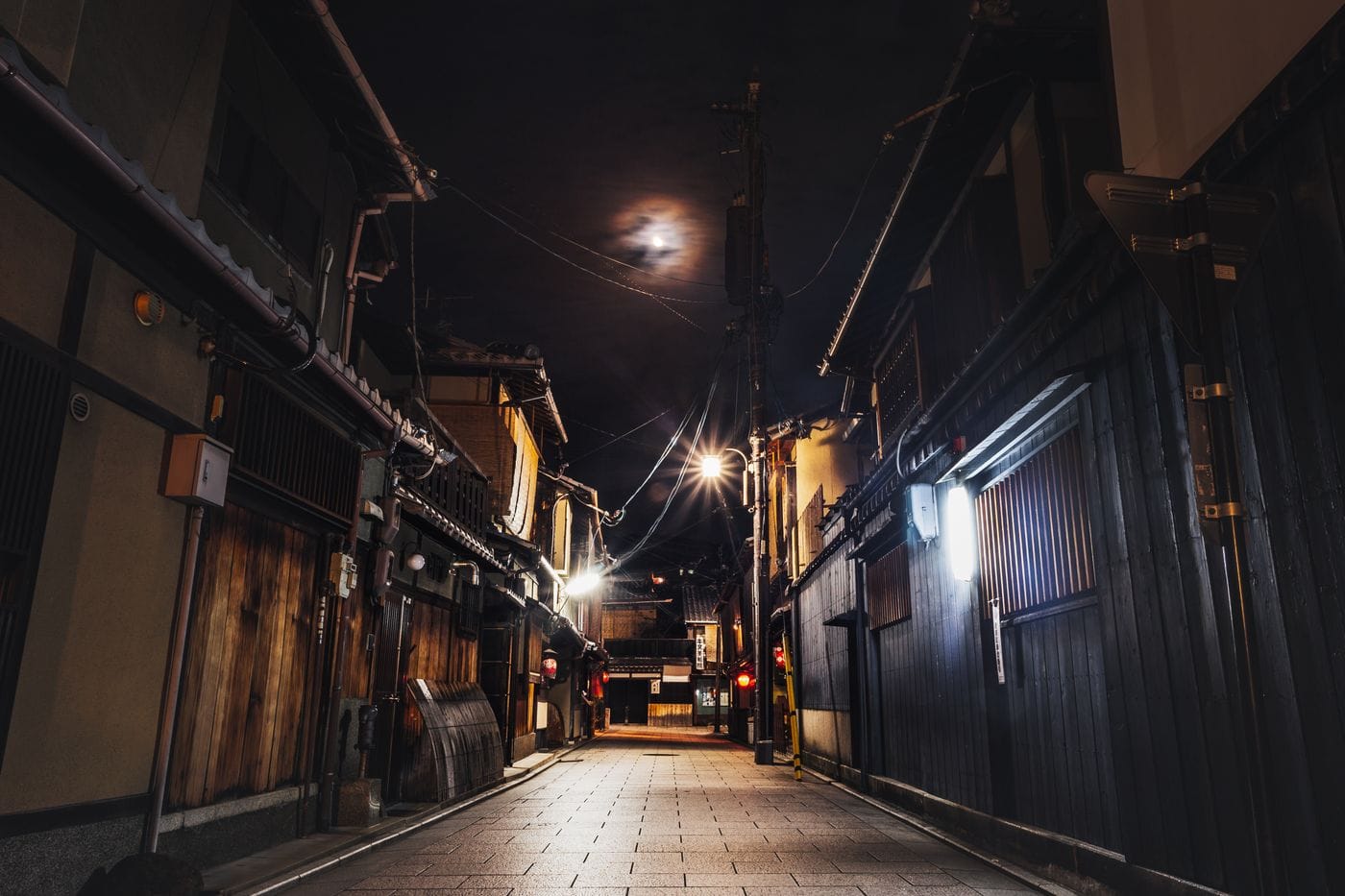 Explore a quiet nighttime alley in Kyoto, Japan, featuring traditional wooden houses and dim street lighting.