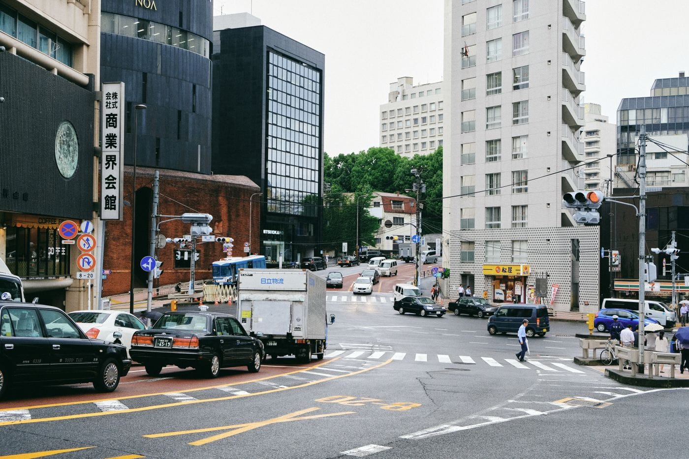 A bustling city street scene at a busy intersection with traffic and pedestrians.