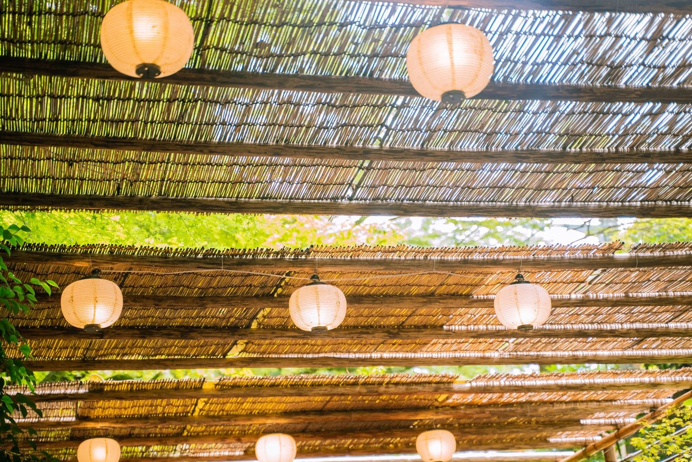 Elegant lanterns hang beneath bamboo ceiling in Kyoto, Japan, capturing the serene summer atmosphere.