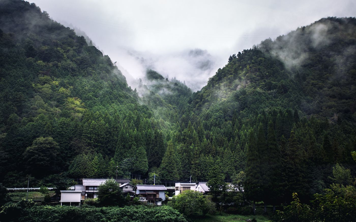 A serene village nestled in lush, misty mountains of Japan.